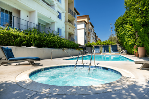 a hot tub and a pool with buildings in the background at Le Blanc Apartment Homes, Canoga Park, 91304